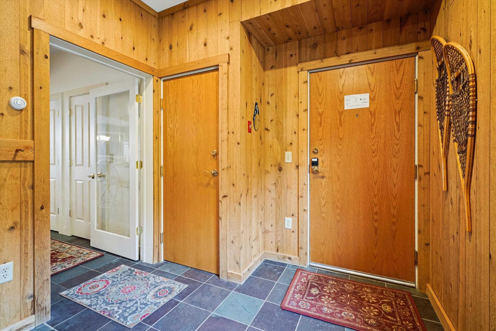 Inviting entryway featuring rustic wood walls, slate tile underfoot, and soft natural light from the large window. The perfect transition from the outdoors to your relaxing mountain retreat.