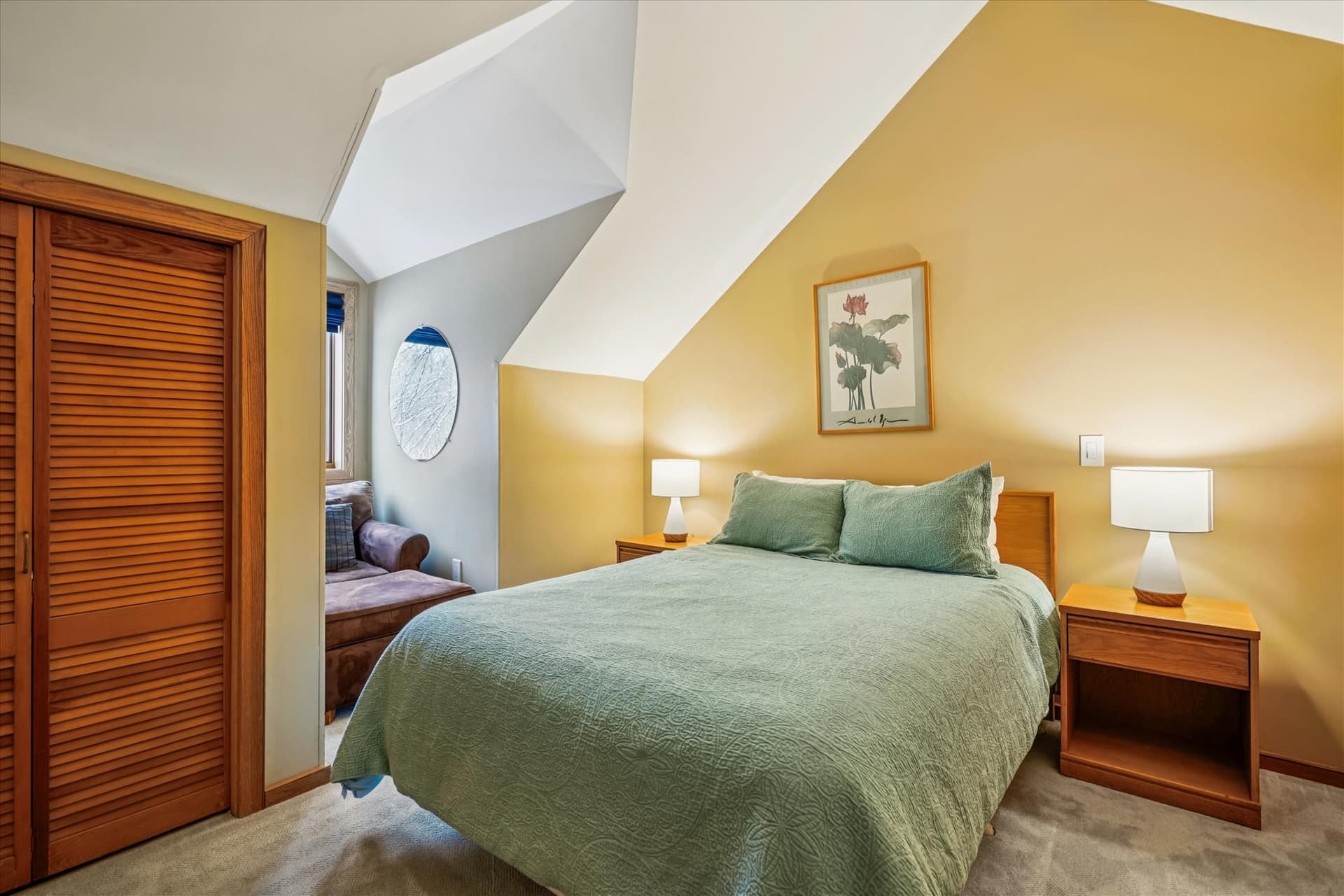 Spacious upstairs bedroom featuring a queen bed, vaulted ceilings, and bedside tables with lamps.