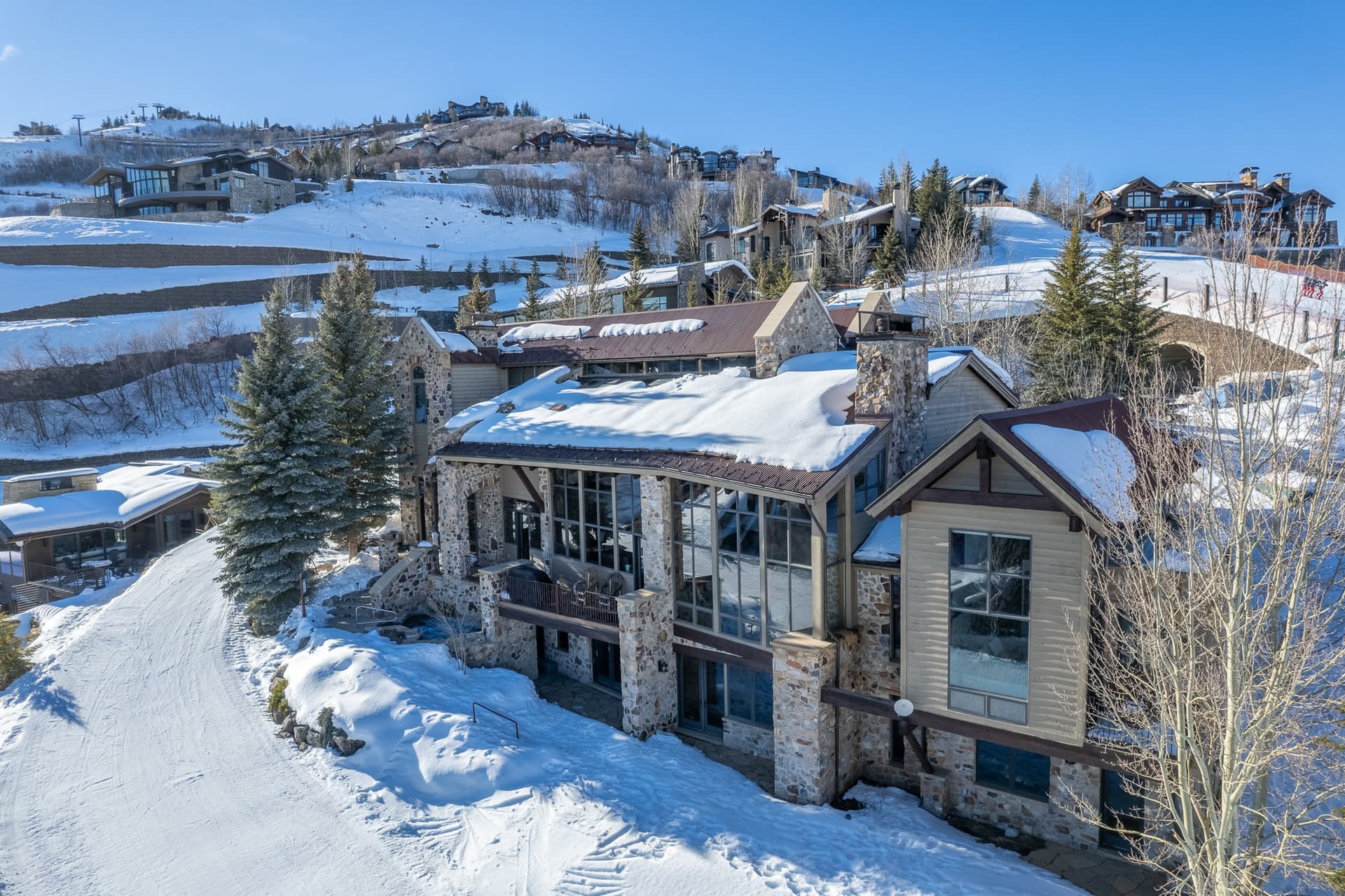 An angled view of the exterior of this luxury Park City rental property, showing the trees and mountains around the home.