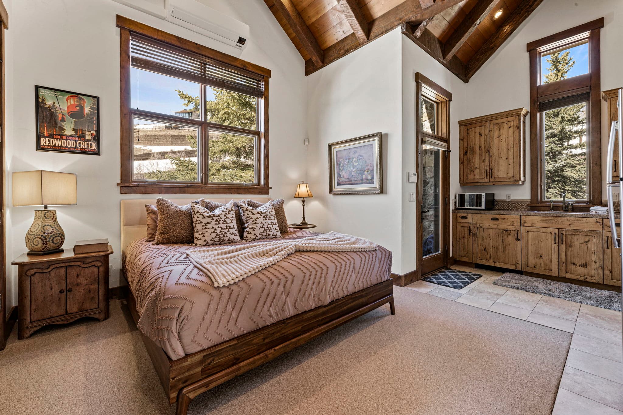 Bedroom with wood furnishings, plush bedding, and kitchenette.