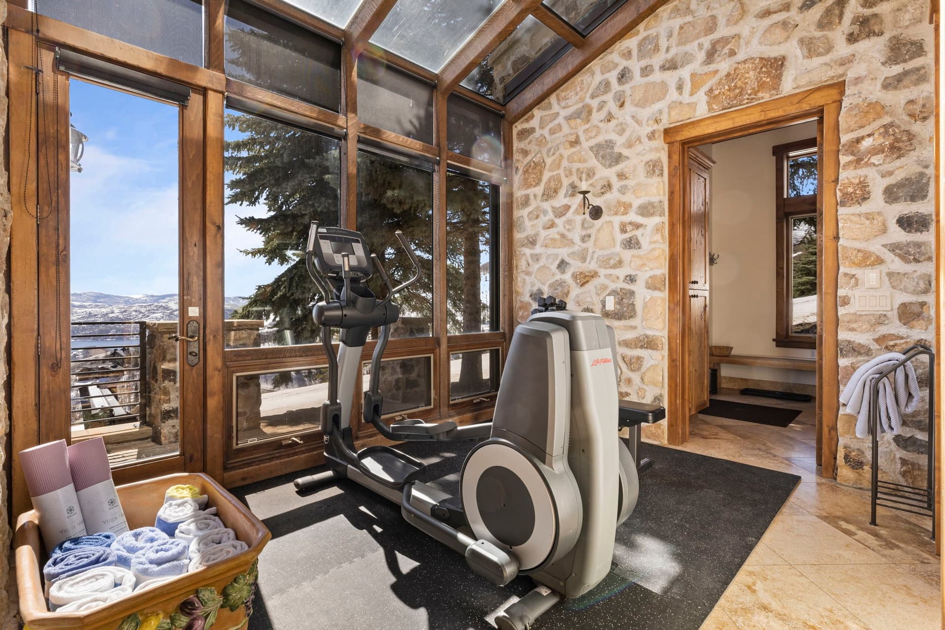Home gym with exercise bike and floor-to-ceiling windows overlooking mountain views.