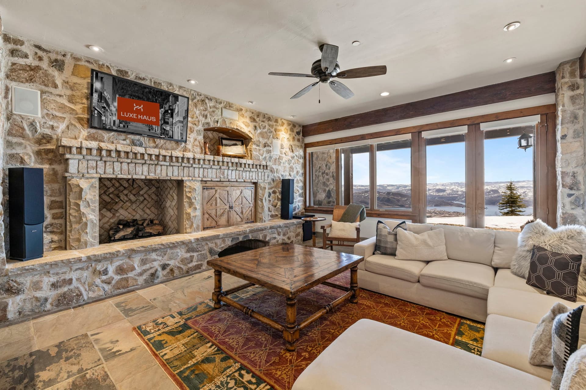 Living space with sectional sofa, stone fireplace, and walk-out patio views