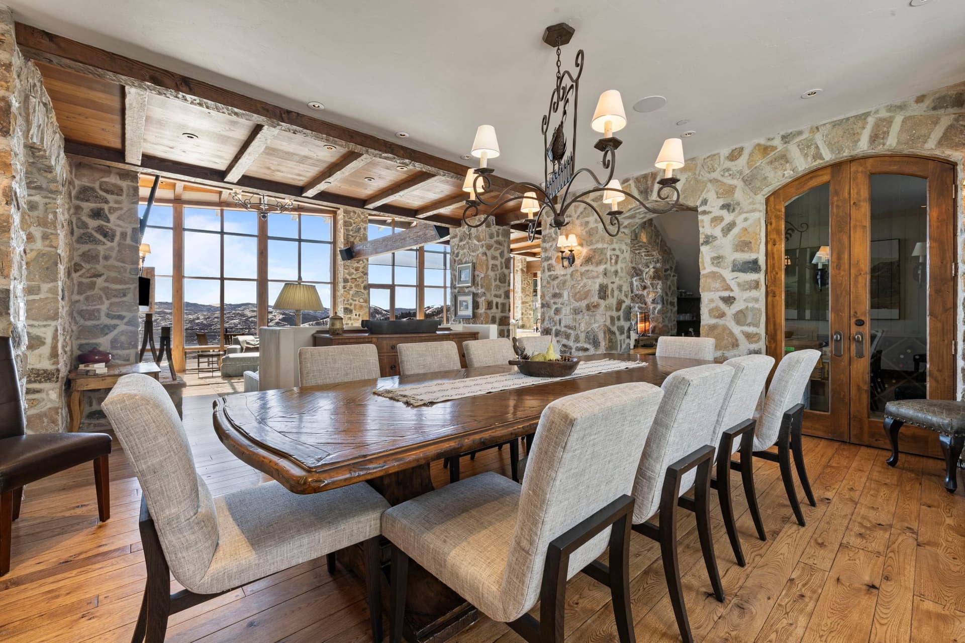 Additional dining space with rustic stone walls, chandelier, and large windows.