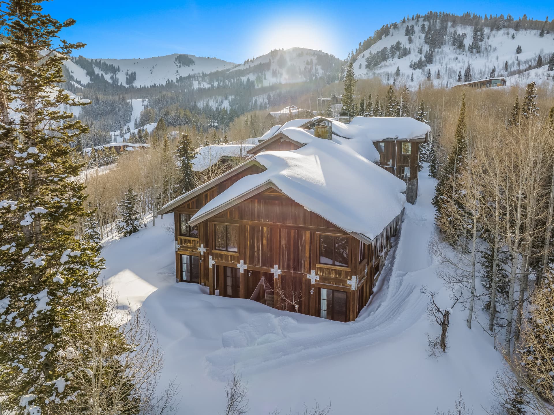 An external look at this luxury Park City vacation rental, snow piled on its roof and the surrounding trees.
