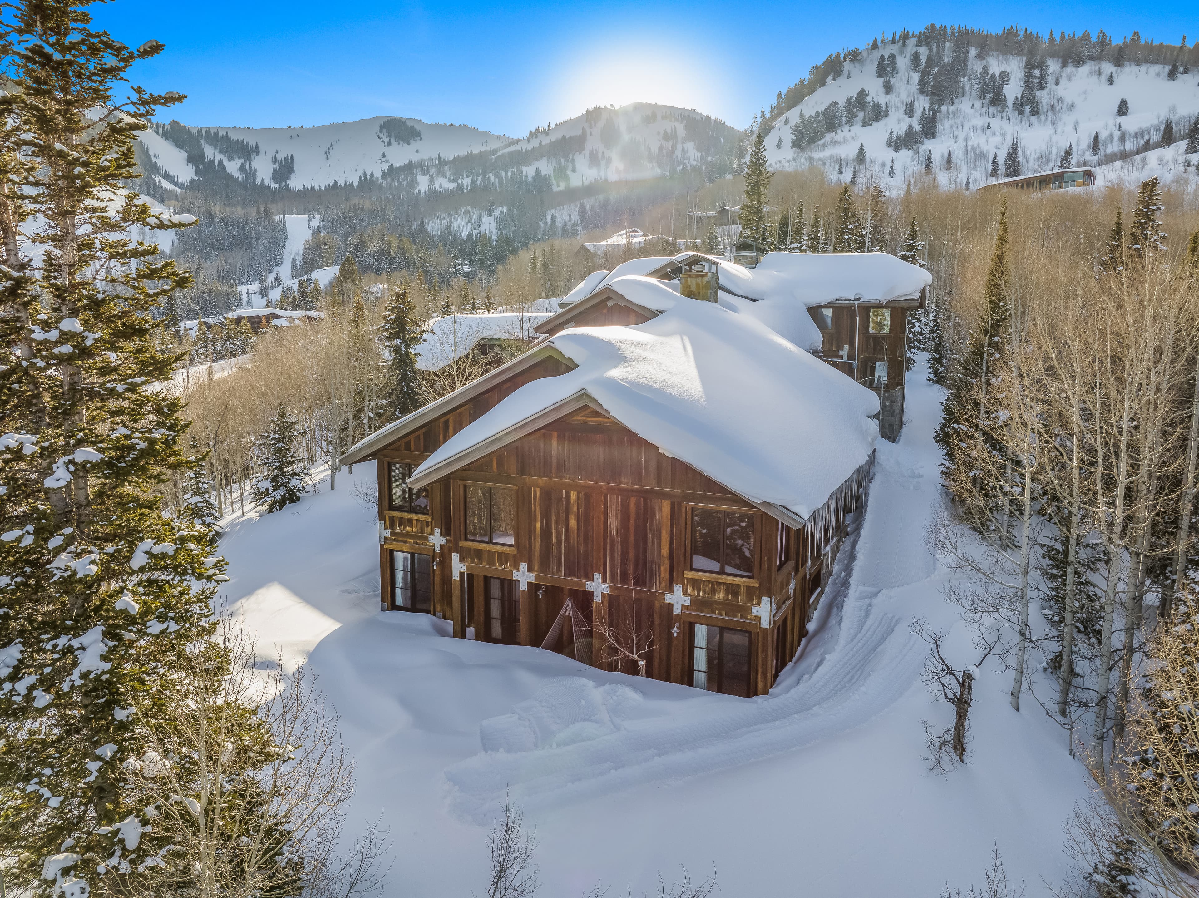 An external look at this luxury Park City vacation rental, snow piled on its roof and the surrounding trees.