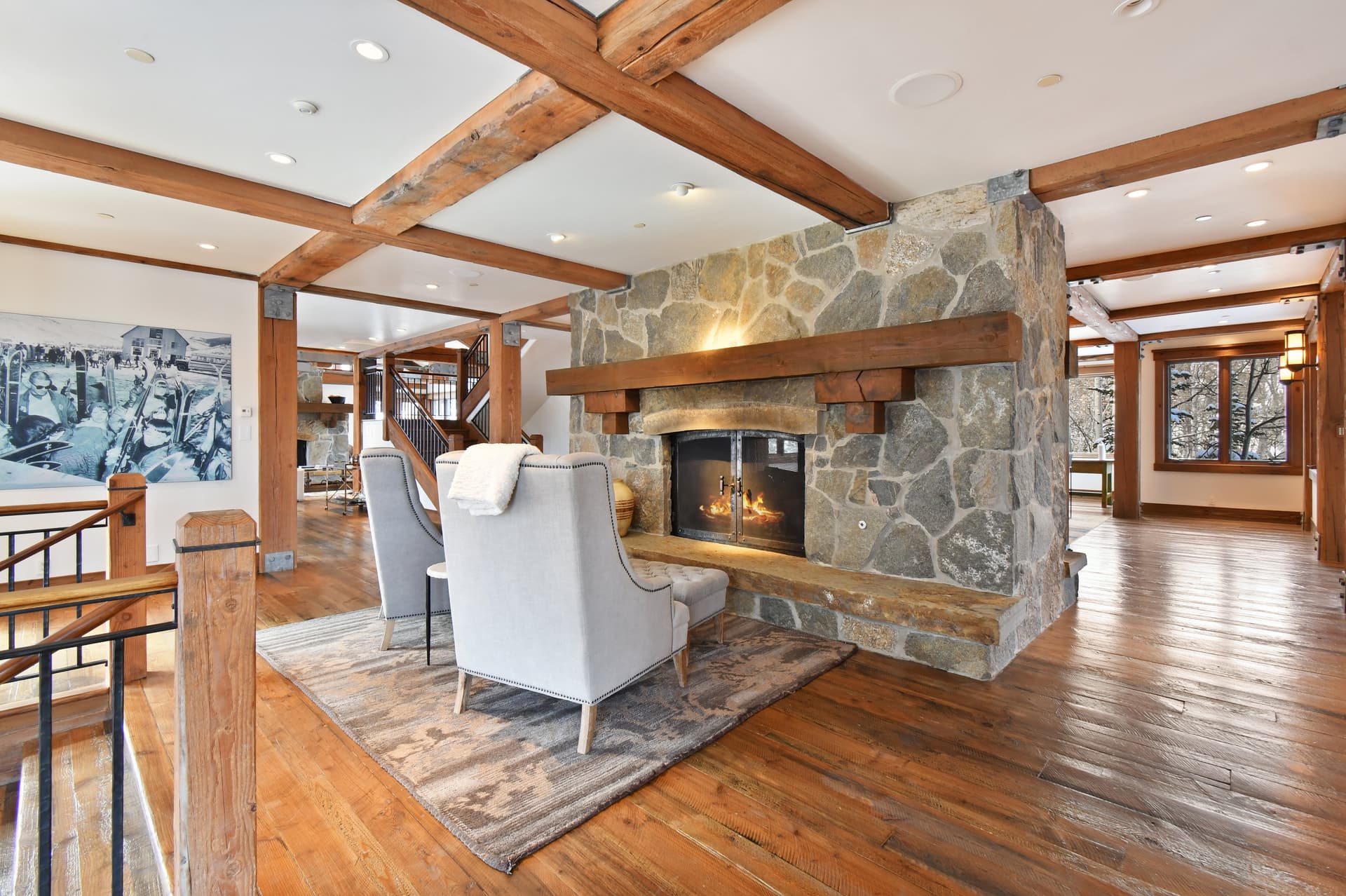 Two cushioned chairs sit in front of a small fireplace built into the center of a room.