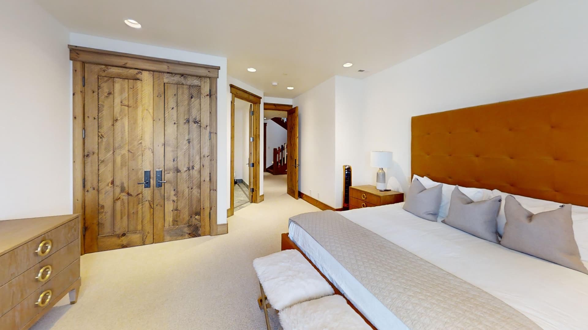 Another view of a bedroom with a red orange bedframe, showing the wooden doors of the closet and the exit doors.