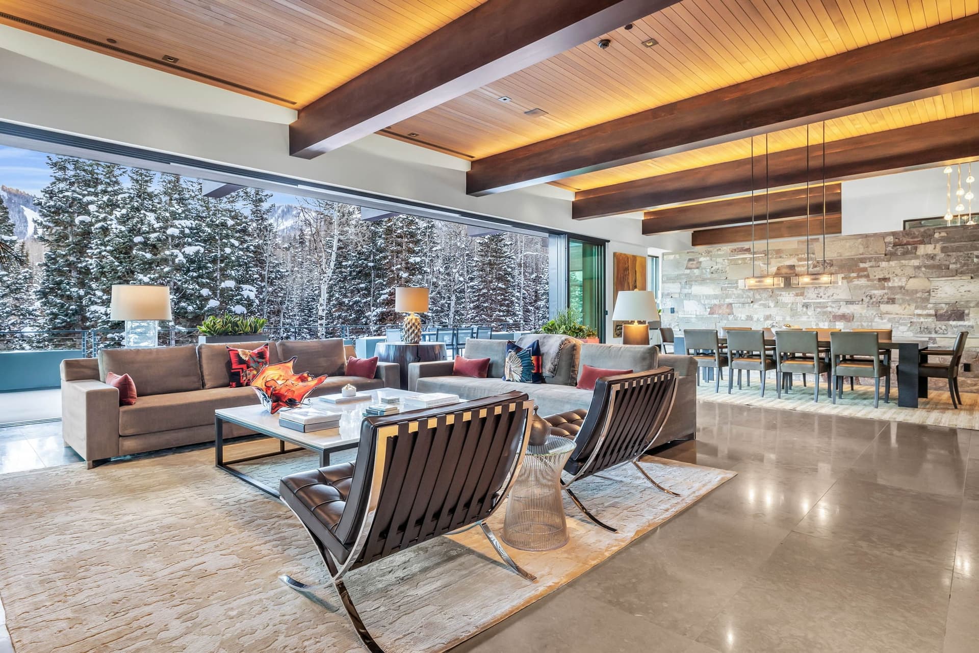 A sleek living space with floor-to-ceiling windows, modern decor, and stunning snowy views.