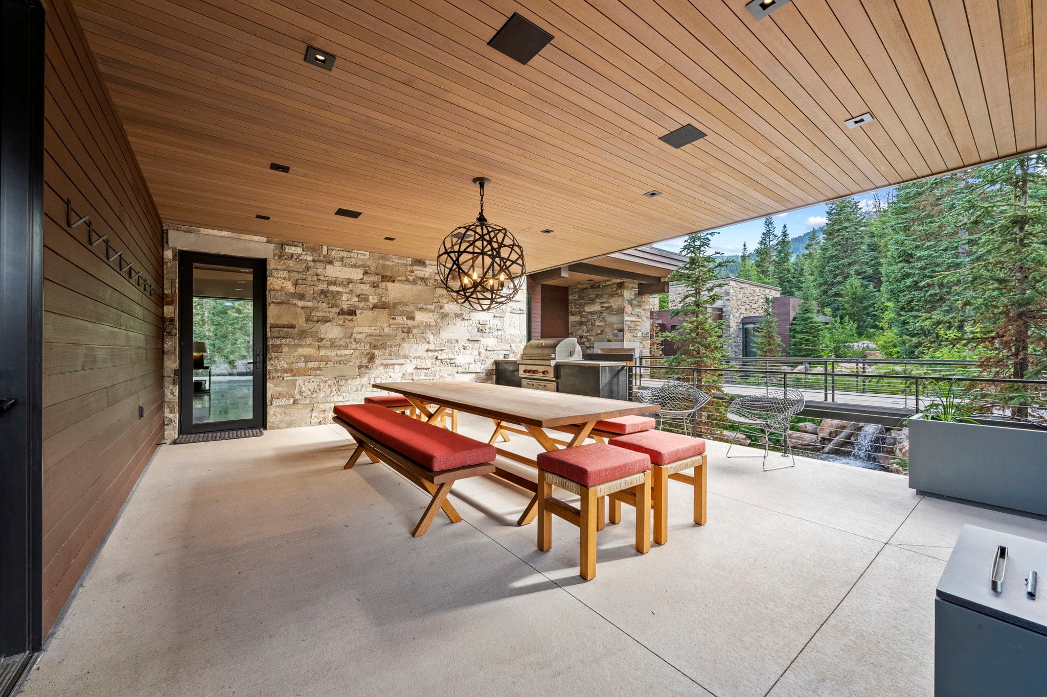 A stylish outdoor dining area with a wood ceiling and scenic backdrop.