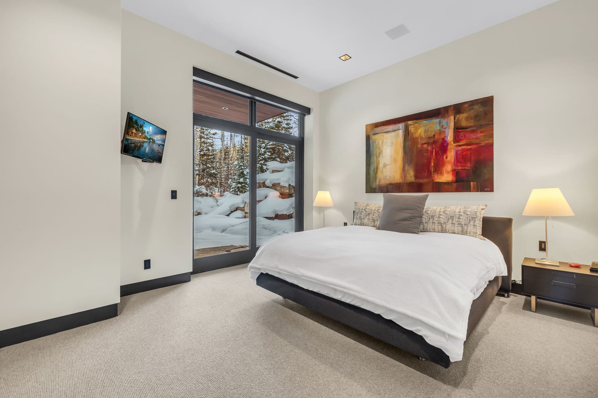 A serene bedroom with outdoor access and snowy views.