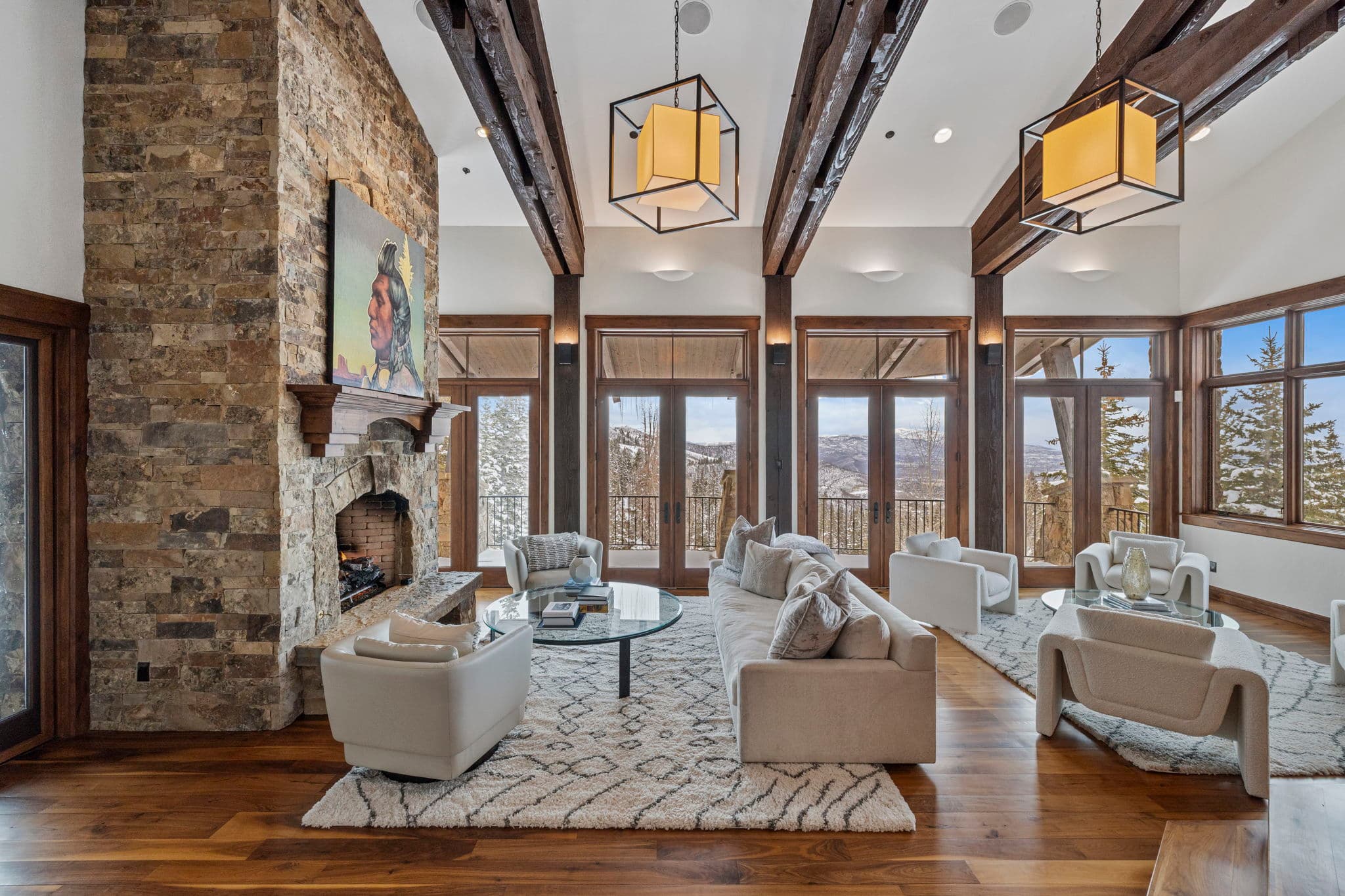 a lofty and elegant living room with a large stone fireplace and white couches
