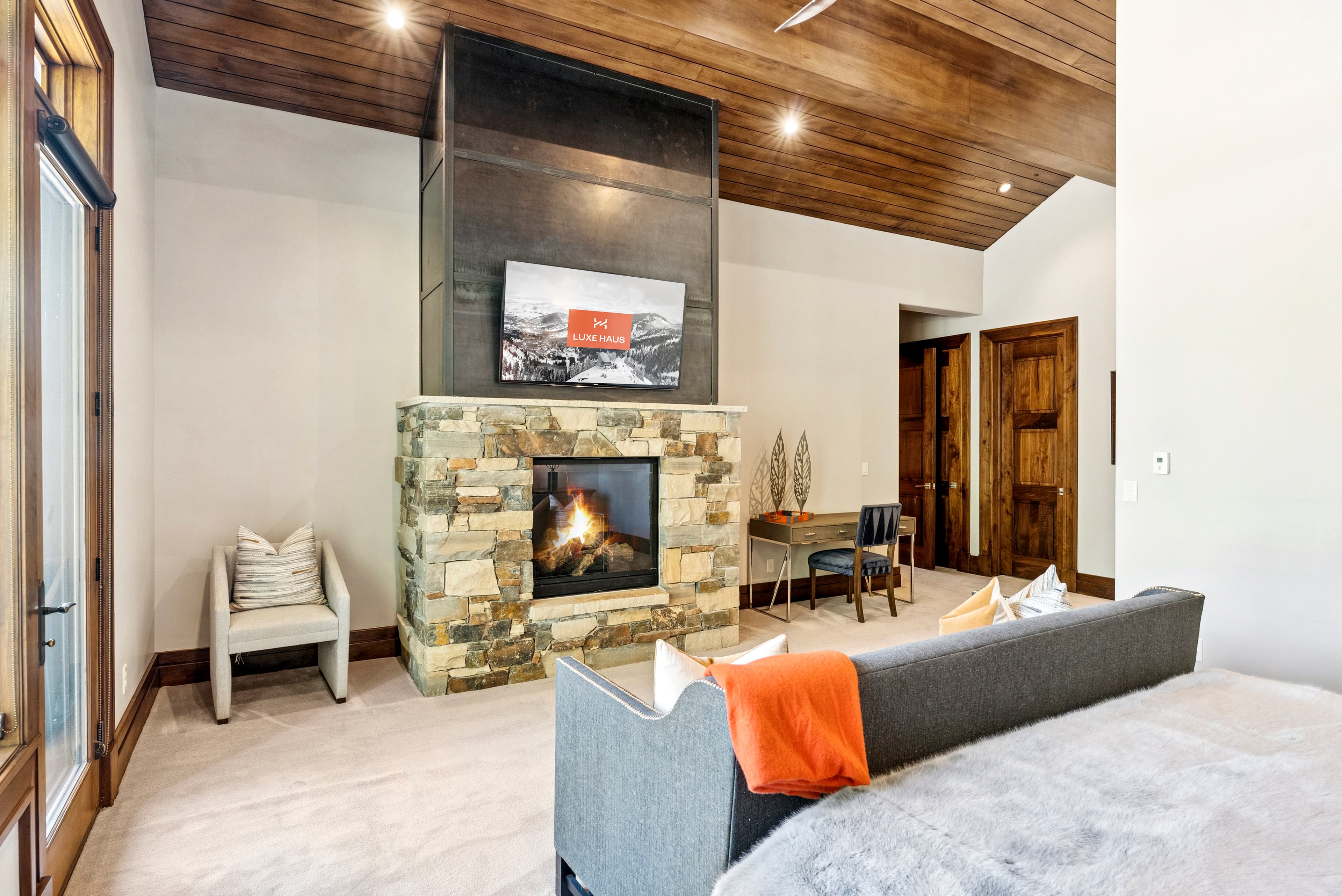 guest suite with modern fireplace and TV above mantle with luxe haus logo on screen