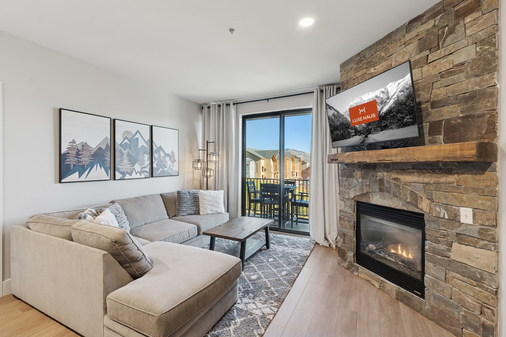 The living room at The Mason with a fireplace, large flat screen TV and mountain views