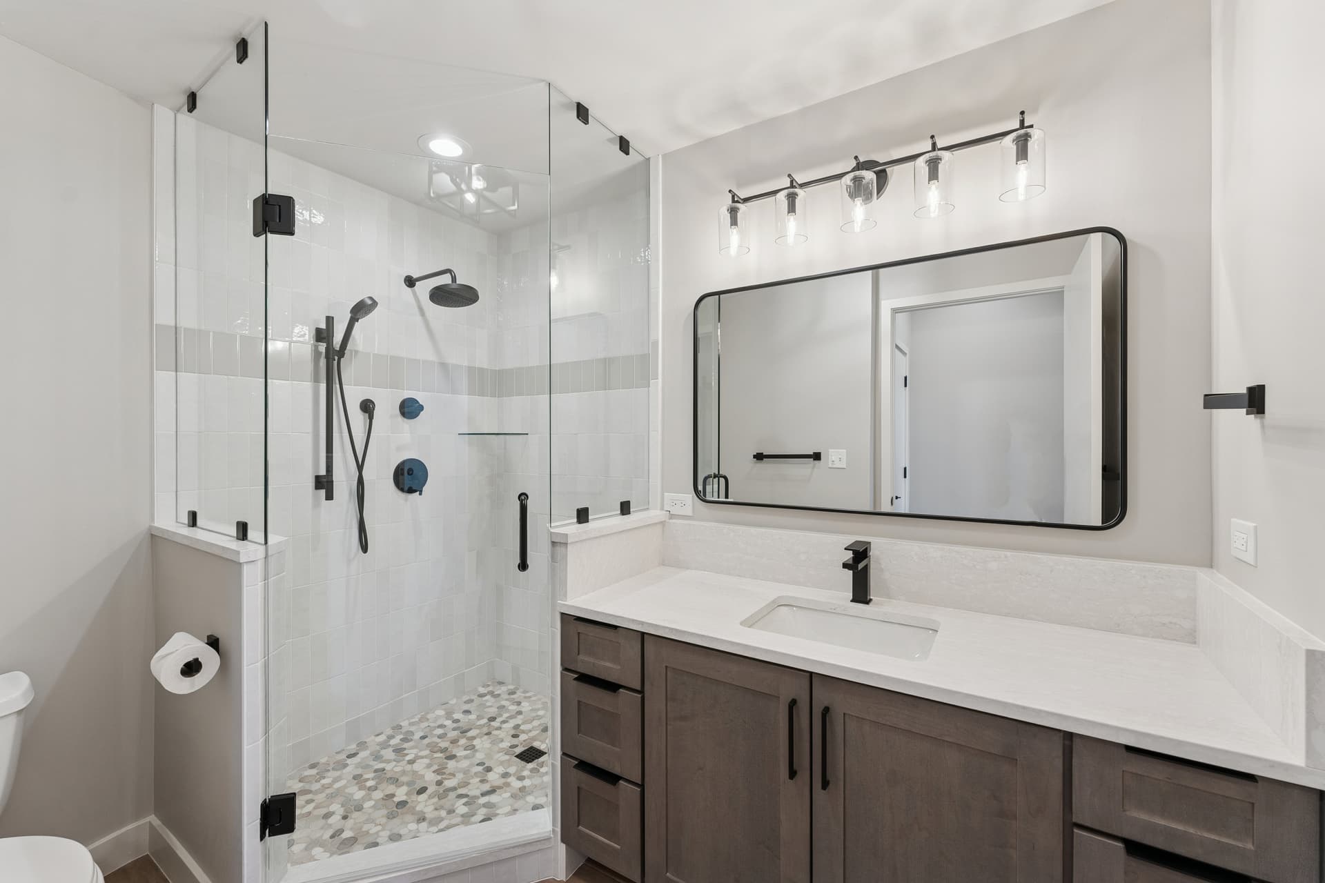Sleek bathroom with glass-enclosed shower, large vanity, and contemporary lighting.